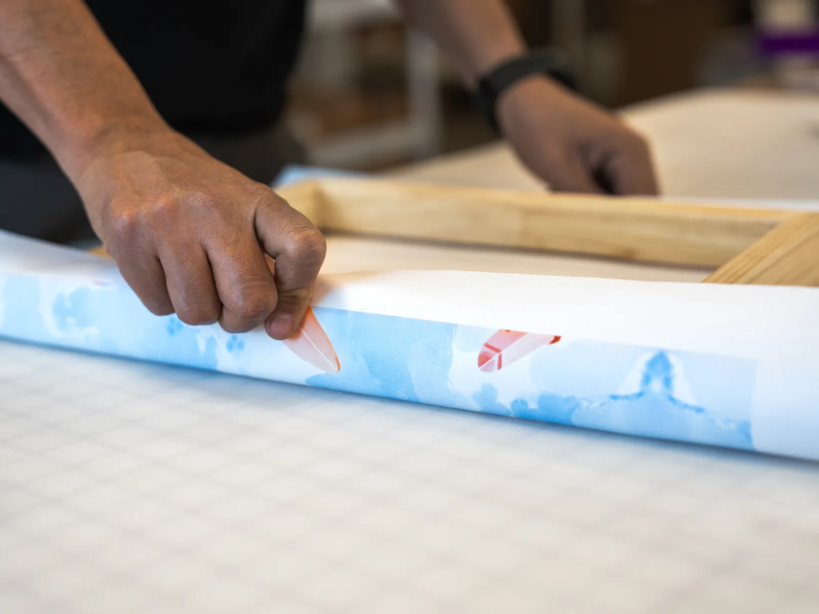 Miguel stretching printed canvas around a frame